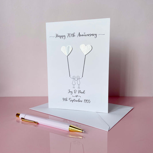 70th anniversary card with silver mirror card hearts and couple illustration on a pink background