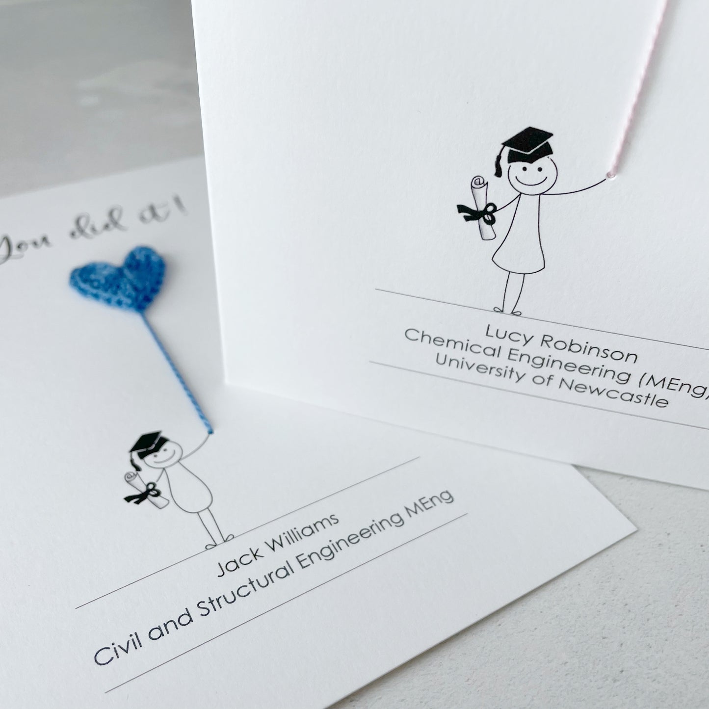 Graduation-themed name tags with stick figure illustrations and text on a light grey background.