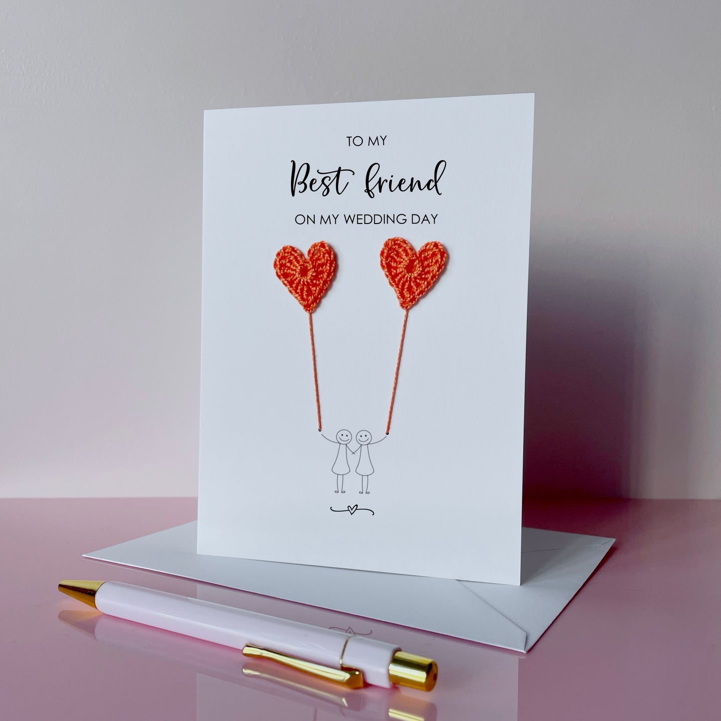Greeting card with orange crochet heart balloons and text on a pink surface. The text at the top of the cad reads 'To my Best friend on my wedding day' 