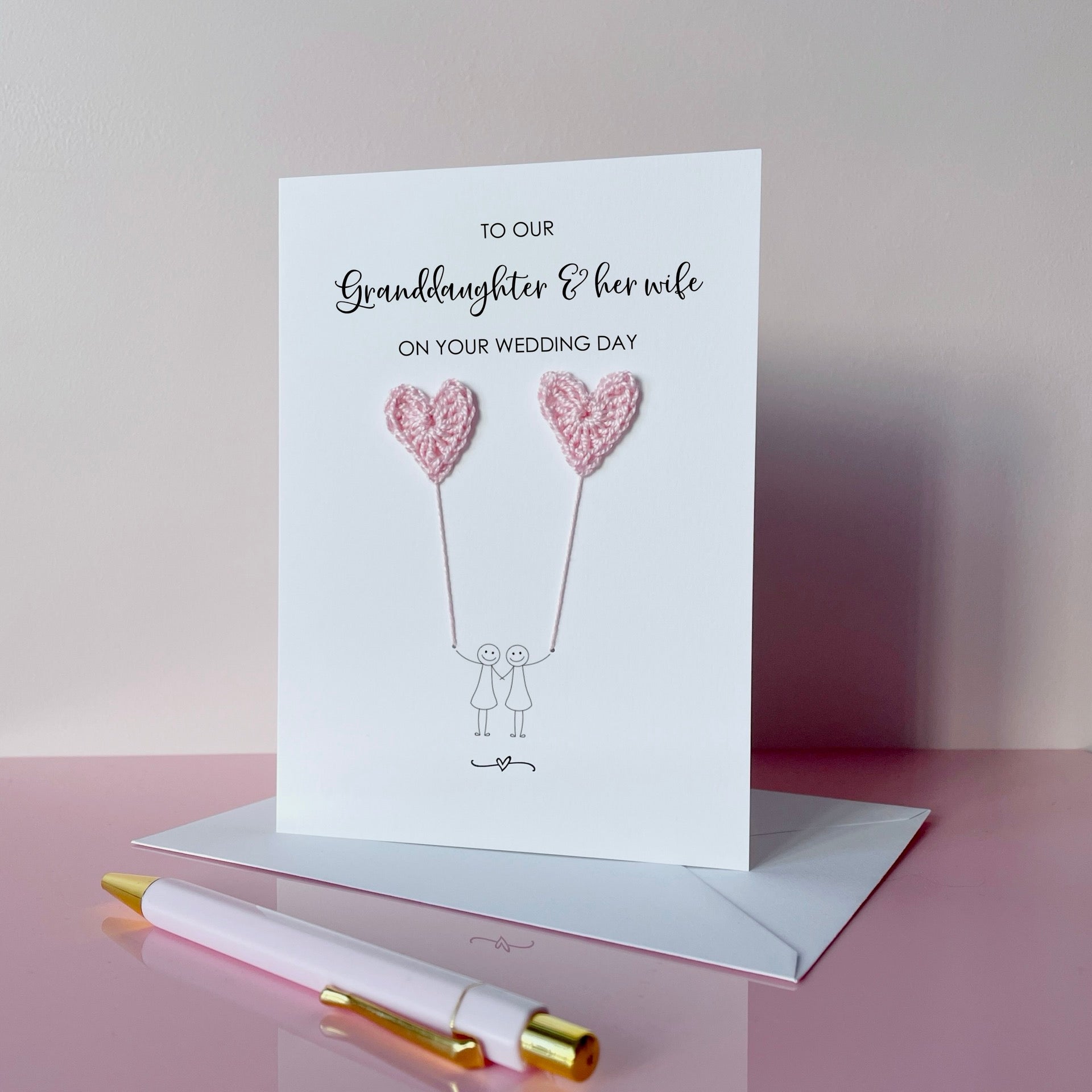 Greeting card with pale pink crochet heart balloons. The text at the top of the card reads 'To our Grandaughter & her wife on your wedding day' 