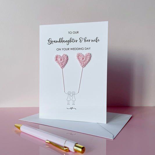 Greeting card with pale pink crochet heart balloons. The text at the top of the card reads 'To our Grandaughter & her wife on your wedding day' 