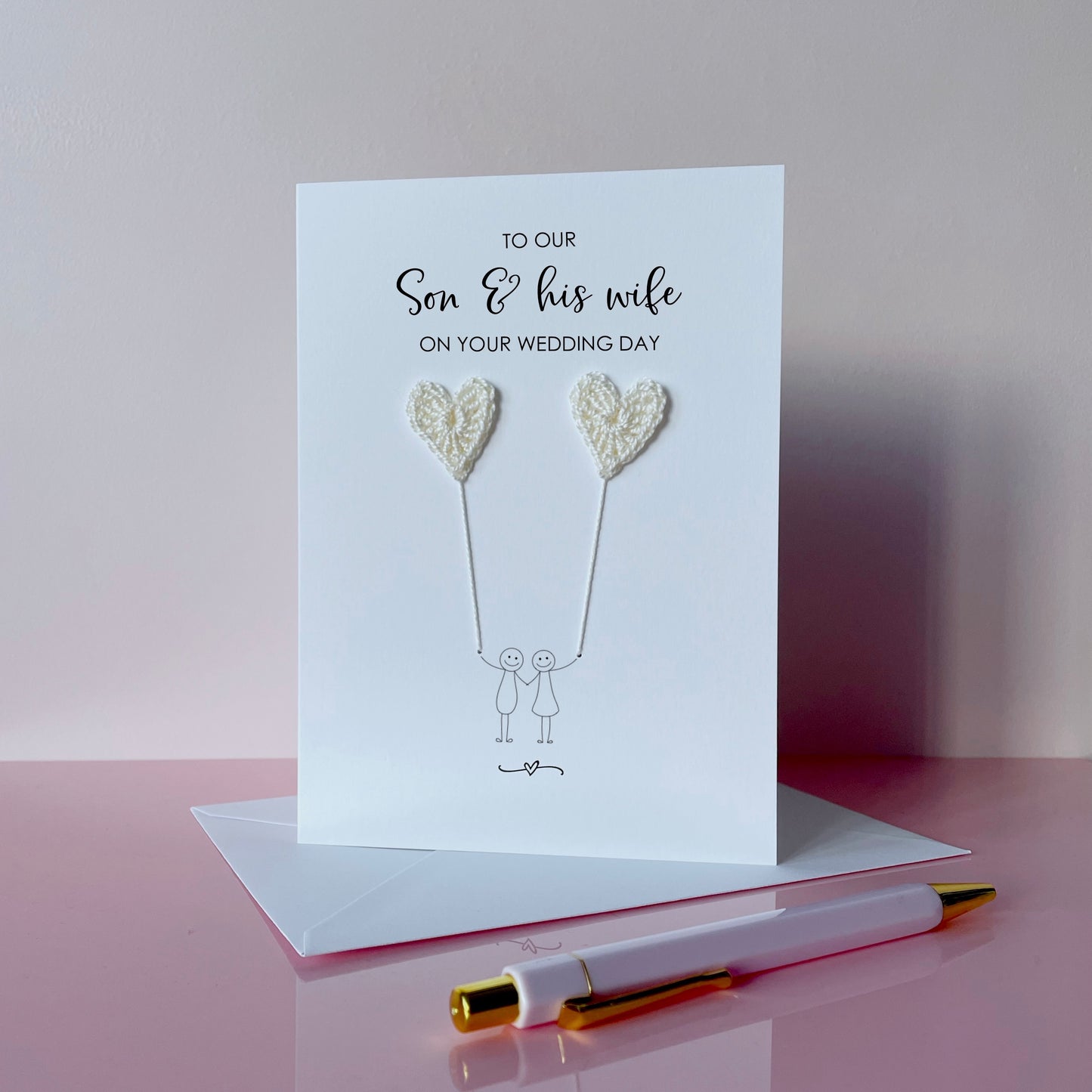 A white greeting card with ivory coloured crochet heart balloons. The text at the top of the cad reads 'To our Son & his wife on your wedding day' 
