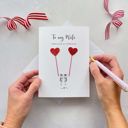 Greeting card with red glitter heart designs and text 'To my Wife with love at Christmas'.