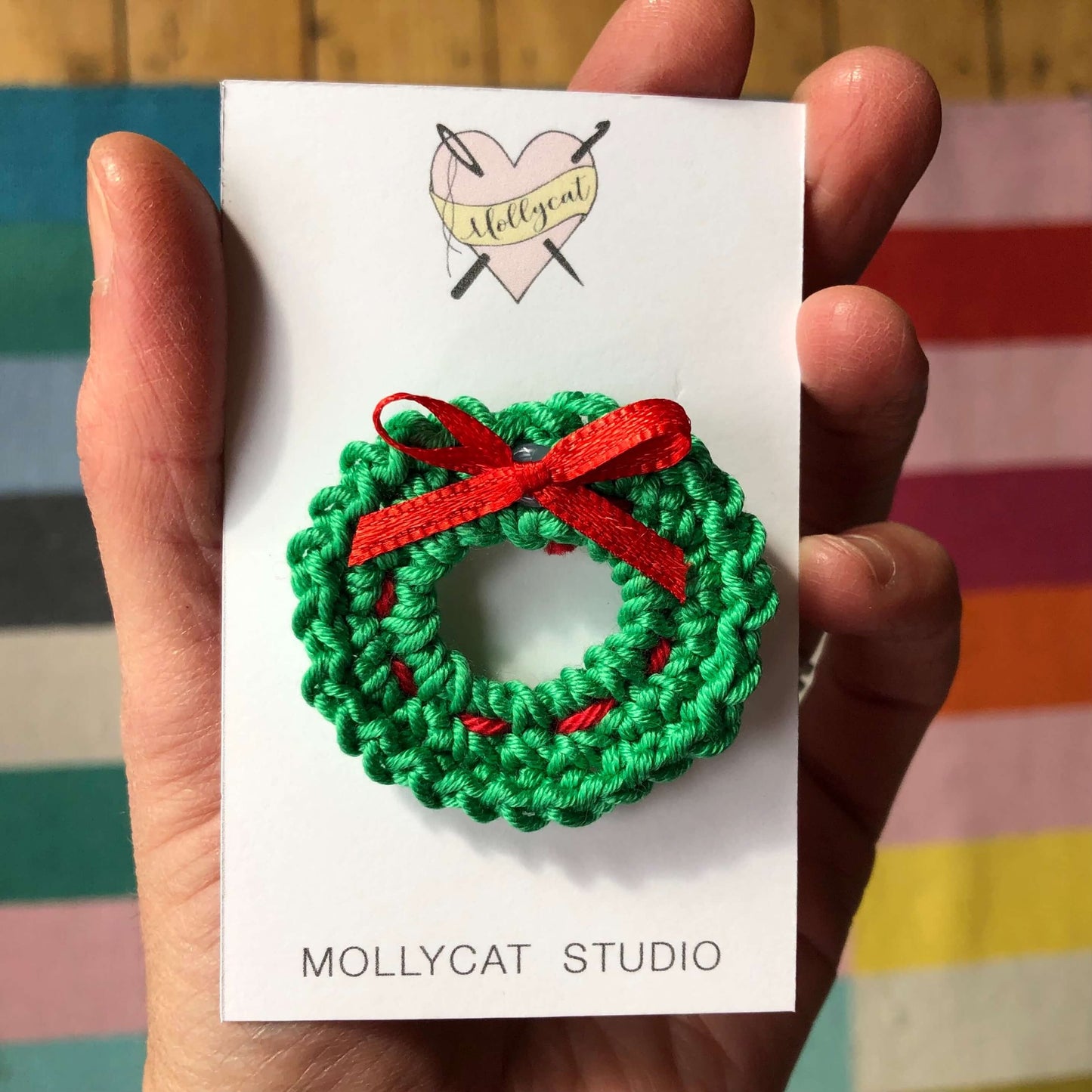 A crochet green and red Christmas wreath , Made by Mollycat Studio - a small business based in Liverpool UK