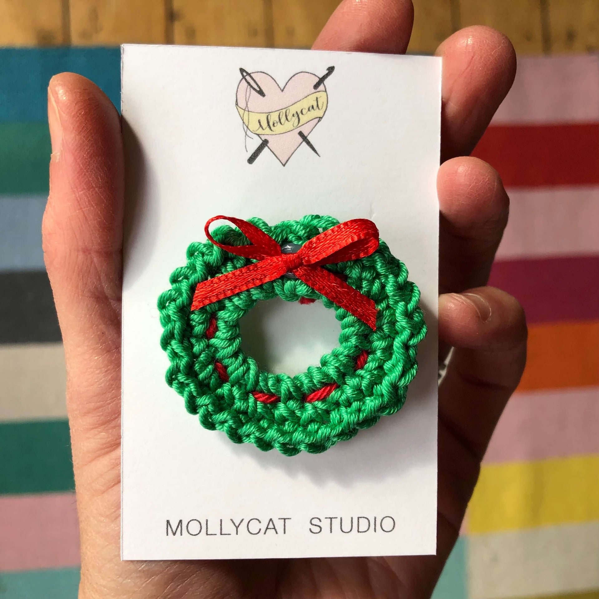 A crochet green and red Christmas wreath , Made by Mollycat Studio - a small business based in Liverpool UK